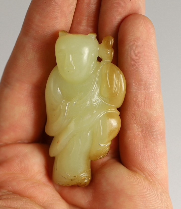 A rare Chinese yellow and russet jade figure of a boy holding a parrot, 18th/19th century, 5.6cm high, wood stand